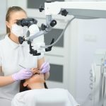 Stomatolog wykonujący leczenie kanałowe pod mikroskopem pacjentce w Klinice Biały Kamień w Nowym Mieście nad Pilicą