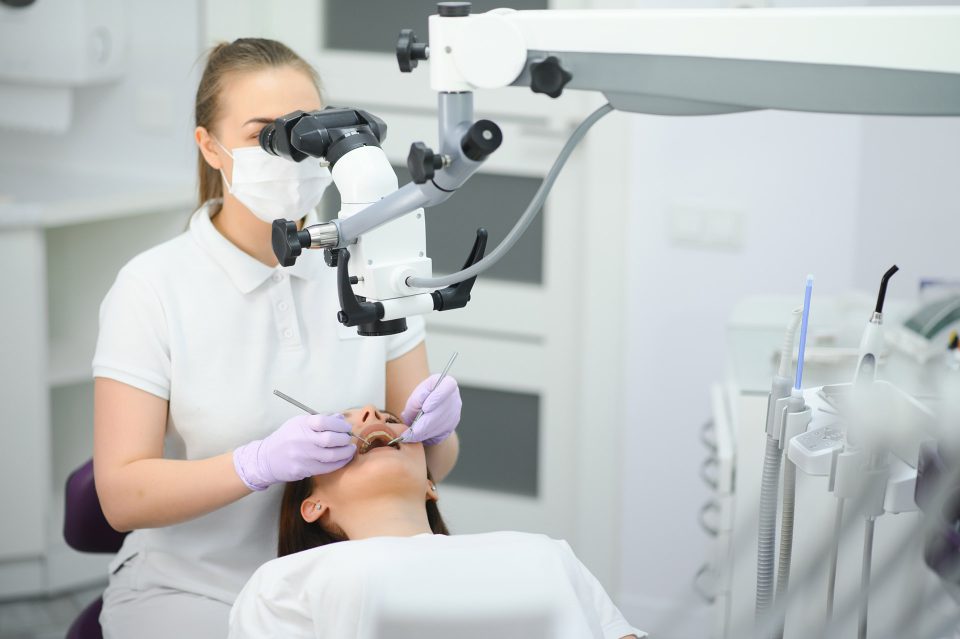 Stomatolog wykonujący leczenie kanałowe pod mikroskopem pacjentce w Klinice Biały Kamień w Nowym Mieście nad Pilicą