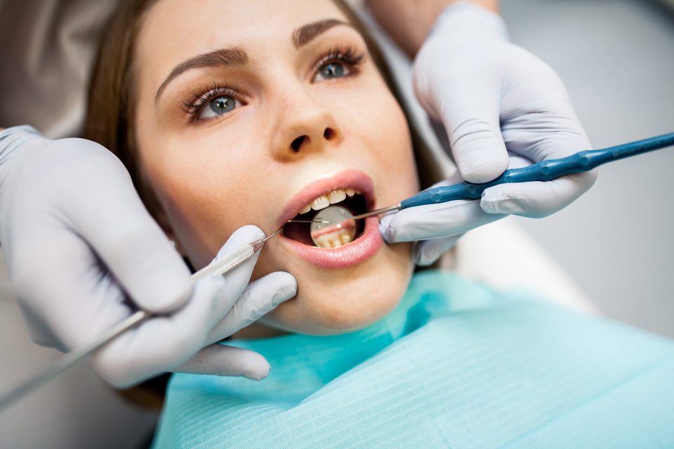 Stomatolog badający dziąsła i przyzębie pacjentki narzędziami dentystycznymi podczas wizyty periodontologicznej w Klinice Biały Kamień w Nowym Mieście nad Pilicą